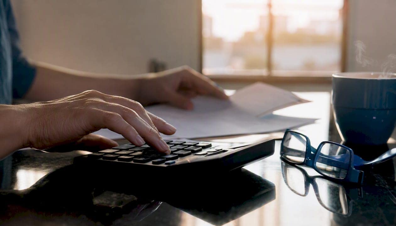 Hands calculating payroll with calculator and cards